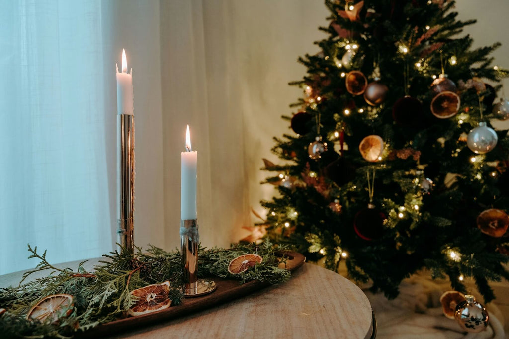 Decorative setup with candles and a Christmas tree in a softly lit room.