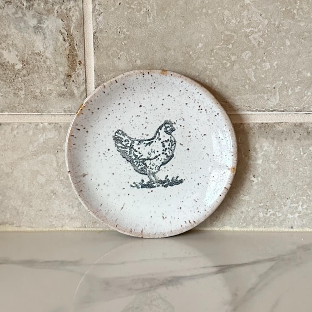 Ceramic plate with a chicken design on a stone surface