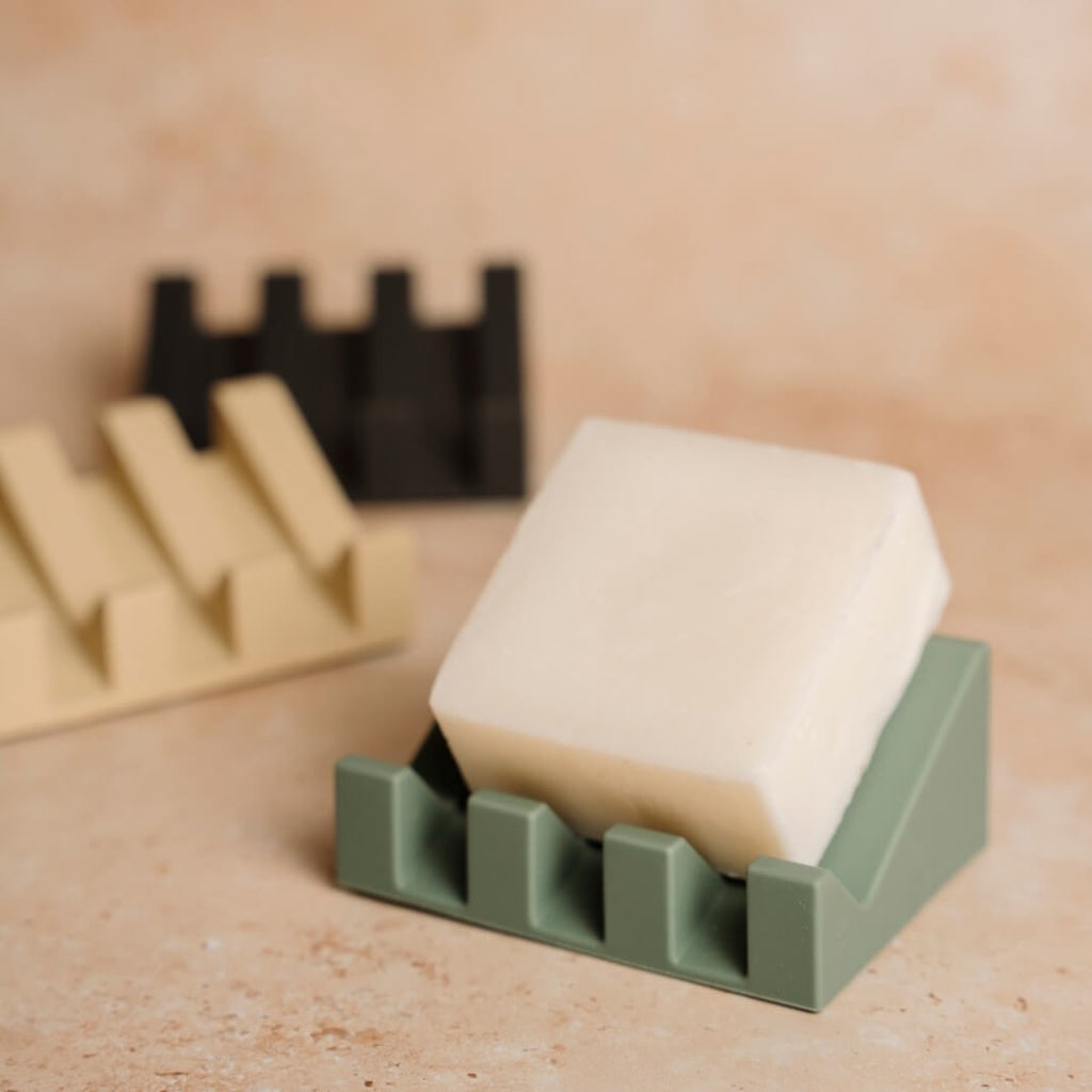 Bar of soap in a green holder on a wooden surface with blurred background