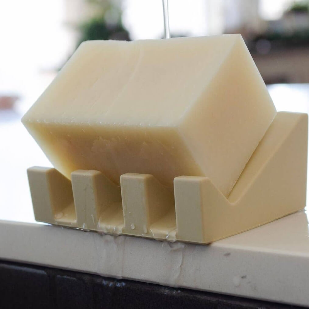 Beige silicone soap dish on a white surface with a blurred background